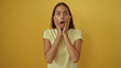 © Krakenimages.com - Young woman with brunette hair showing shocked expression over isolated yellow background with hands on face