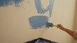 © Krakenimages.com - Woman painting wall with blue paint brush indoors, showcasing diy home renovation in new apartment with natural light.