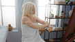 © Krakenimages.com - Woman in spa applying lotion on arm in a serene wellness center, showcasing middle-aged caucasian beauty and self-care routine indoors, with shelves in the background.