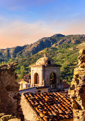 Wall Mural - View of medieval italian town in mountain valley of Sicily, Italy. Old town in a valley among green mountains with ancient church and vintage roofs of buildings in beautiful evening sunset light