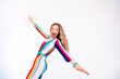 © deagreez - Young woman in colorful striped overall poses joyfully against a white background, capturing a vibrant and youthful style