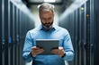 © Sergio - IT professional monitors server performance using a tablet inside a data center during the afternoon shift