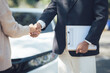 © Kritdanai - Successful Car Deal: A handshake seals the deal between a car salesperson and a customer, signifying a successful car purchase.  The clipboard with paperwork hints at the finalized transaction.