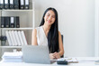 © Kritdanai - Confident Businesswoman at Desk: A portrait of a smiling Asian businesswoman sitting at her desk, confidently looking at the camera. She exudes professionalism and success.