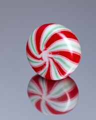 Wall Mural - Red and Green Swirl Candy on Reflective Surface Captured in High Detail, Perfect for Holiday Themes and Treats