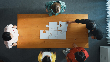 Wall Mural - Top down view of skilled business people assemble jigsaw puzzle on meeting table. Group of diverse team working together to solve the puzzle. Represented unity, togetherness, cooperative. Convocation.