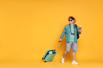 Wall Mural - Traveller with passport and suitcase on yellow background. Space for text