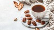 © ArtificialHorizons - Coffee cup with pecan nuts on marble coaster surrounded by autumn leaves and knitted fabric Copy Space