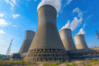 © Mediaphotos - Cooling towers of a power plant emitting steam under clear sky with visible power lines in background indicating industrial environment and energy production