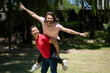 © Mariano - Couple of friends having fun in a park riding a piggyback