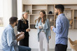 © fizkes - Group of four multiethnic young and older employees enjoy talk during coffee break in modern workplace, having fun, joking, looking satisfied with friendly, informal conversation met in office lobby