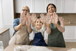 © fizkes - Having fun on kitchen. Cute family portrait laughing 3 female generations mature granny young mommy little tween child girl knead dough bake cake pastries together look at camera show palms in flour