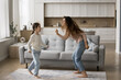 © fizkes - Crazy day. Laughing millennial single mom little preteen age kid daughter jump dance barefoot on warm carpet at modern studio apartment celebrate free weekend at home excited about becoming homeowners