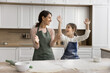 © fizkes - Funny bakery. Candid laughing grownup elder younger sisters young mom little kid daughter enjoy easy cooking food at home play chat clap hands in floor when rolling dough for pasta having fun together