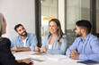 © fizkes - Diverse office employees take part in seminar led by mature 40s businesslady, laughing together engaged in friendly, informal conversation seated at conference table in office. Companionship, teamwork