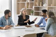 © fizkes - Mature experienced team leader sharing thoughts, point of view during briefing with diverse, young staff members. Negotiations process, seminar of corporate training event in company conference room