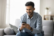 © fizkes - Good news in message. Smiling confident millennial man relax at living room sit on couch use cellphone device to send get sms chat in messenger enjoy virtual dating in web app check social media pages