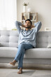 © fizkes - Tranquility and mindfulness. Vertical shot young man tired after work enjoy serene moment on weekend chill at home rest relax sitting on sofa at living room with closed eyes restore emotional balance
