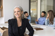 © fizkes - Pensive middle-aged 55s businesslady sit at desk look into distance with optimistic expression, distracted from meeting with staff, dreaming about future business growth and professional opportunities