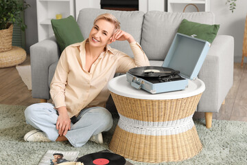 Wall Mural - Mature woman with record player sitting at home