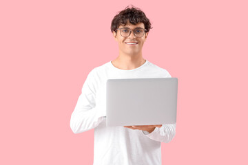 Male programmer with laptop on pink background