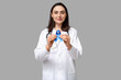 © Pixel-Shot - Young female doctor with blue ribbon on grey background. Colon cancer awareness concept
