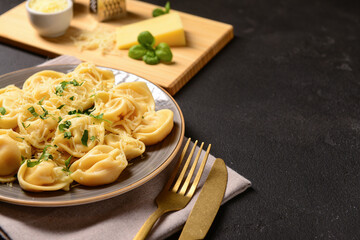 Wall Mural - Plate of boiled dumplings with cheese and basil on black background