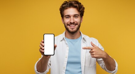 Young man pointing at smartphone showing a white empty screen game, bet, lottery win isolated over yellow background. Product placement for mobile application advertisement.

