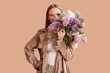 © Pixel-Shot - Beautiful young woman with bouquet of lilac flowers on beige background