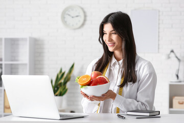 Sticker - Female nutritionist with healthy food video chatting at table in office