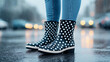 © Sana Sabina - Fashionable individual wearing polka dot rain boots standing in the rain on a wet street backdrop, showcasing style and resilience in inclement weather.