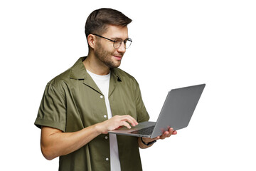 Man wearing glasses smiles while using a laptop and standing indoors in a modern environment