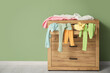 © Pixel-Shot - Commode with scattered clothes near green wall in room