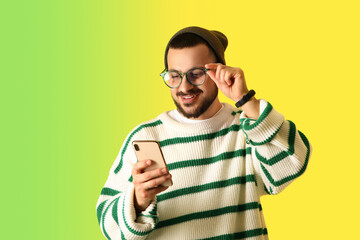 Wall Mural - young man using mobile phone on color background