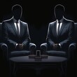 © armaya - Two anonymous men in suits sit opposite each other at a low table.