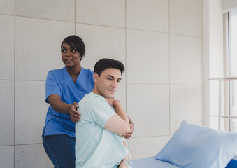 Wall Mural - Patient caucasian man with woman nurse black people carer physical therapist two person sitting talk helping support give advice and holding relax massage on back body in room service hospital clinic