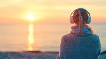 Wall Mural - woman listens to music with headphones as she peacefully observes a vibrant sunset over the ocean, c