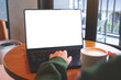 © Farknot Architect - Mockup image of a woman typing on laptop computer with blank white desktop screen while drinking coffee in cafe