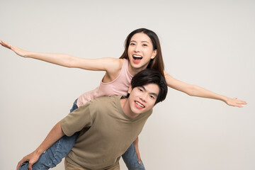 Wall Mural - Piggyback ride Happy asian couple attractive in various action gesture standing on isolated white background. Cheerful Smiling young man and woman fun with piggyback ride