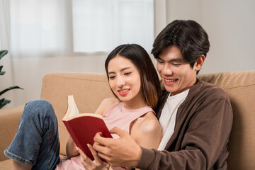 Wall Mural - Happy moment of asian family man and woman husband and wife just married buying new house. Relax reading book on sofa in living room