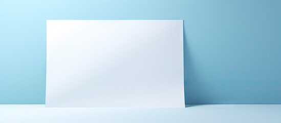 Leinwandbilder - Blank white paper positioned on a soft blue background with shadow effects creating depth and an invitingly simple layout for copying space.