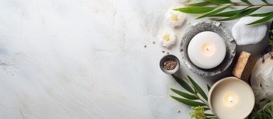 Poster - Spa setting with white candles in gray and cream stone holders, surrounded by green leaves and white flowers on a light marble background.
