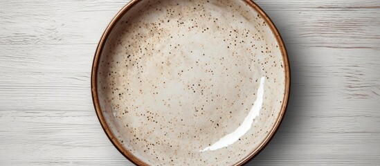 Leinwandbilder - Top view of a rustic brown ceramic plate with speckled texture on a white background showcasing its subtle elegance and artisanal design