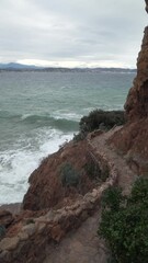 Wall Mural - Landscape view of splash ses waves breaking a rocky cliff with gray cloudy sky on the horizon