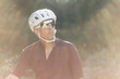 © Cavan Images - Cyclist in a white helmet gazing upward, soft lens flare in focus.