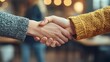 © Anjar Stock - A close up handshake between two people wearing a gray and yellow sweater shows connection
