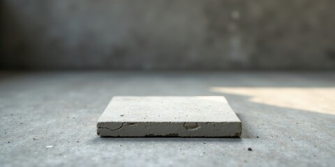 Aufkleber - A Rough-Textured Concrete Slab Rests on a Grey Floor with Subtle Lighting