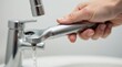 © supansa - Close-up of a hand using a wrench on a faucet with water running