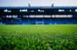© Ackbara Studio - A lush green soccer field under natural light, with a blurred stadium creating a serene sports environment. Ideal for soccer-themed marketing, wallpapers, or branding materials.
