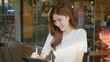 © ParinwatDop - woman is sitting at cafe, drawing on tablet with stylus, smiling. warm sunlight illuminates her face, creating cheerful atmosphere. businesswoman remote work digital nomad